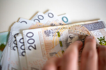 Fingers touching stack of 200 Polish złoty notes