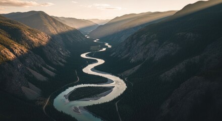 Aerial view of a winding river snaking through a mountain valley at sunset