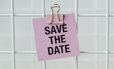 A white sticky note with the words save the date written in uppercase letters is placed white background