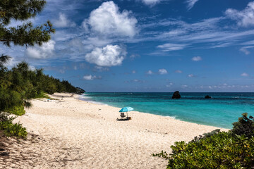 Serene Jobson's Cove, Bermuda: Crystal-Clear Turquoise Waters, Sandy Shore, and Rocky outcrops Under a Bright Blue Sky with Scattered Clouds