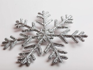 Sparkling silver snowflake decoration shining on a white surface during winter holiday season