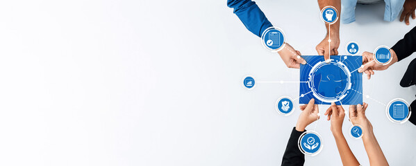 A team collaborates over a digital interface, showcasing business analytics and icons, representing a modern approach to teamwork and strategic planning in a bright workspace. Amity