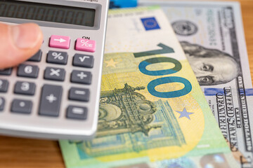 Euro and dollar money. Eurozone and US banknotes and a pocket calculator held in a hand. Financial concept, currency exchange, market rate, euro-dollar pair analysis