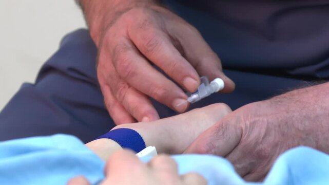  A close-up view of a hemodialysis machine during setup. A person in gloves is carefully connecting tubes to the equipment, which features red and clear tubing, a filter, and various connectors.