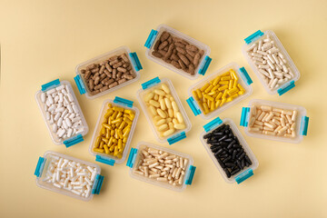 Vitamins, minerals and dietary supplements in containers from above on yellow background. Assortments of many colored pills, tablets, capsules and food supplements. Healthy lifestyle.