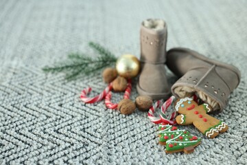 Saint Nicholas day tradition. Boots with sweets and festive decor on floor indoors, space for text