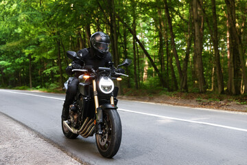 Fototapeta premium Young man in helmet driving modern motorcycle outdoors. Space for text