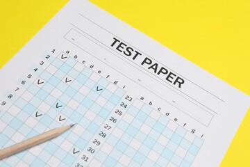 Answer sheet and pencil on yellow background, closeup. Student passing exam