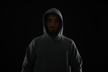 Criminal man in hood on dark background