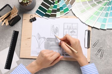 Woman drawing sketch of room interior at grey table, top view