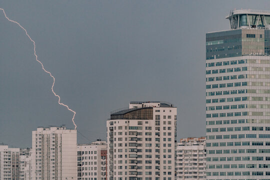 Lightning strikes over urban buildings during a stormy evening