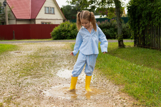Child splashing in puddle with yellow boots
