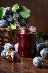 Plum jam and fresh berries on a brown vintage table.