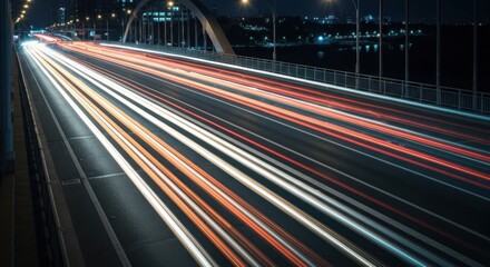 Night traffic trails on a city bridge.  Light streaks from moving vehicles across a highway at night