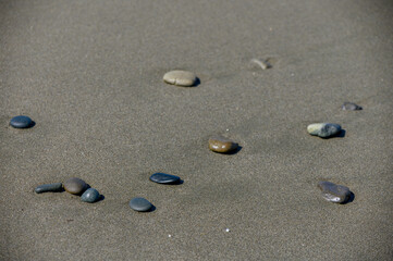 Smooth sea pebbles on sandy beach as natural background