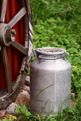 A large metal bucket sitting next to a wooden wheel