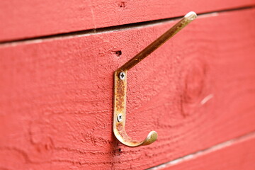 A close-up shot of a metal hook attached to a bright red wall, great for abstract or architectural uses
