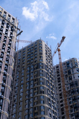 New skyscraper construction in urban area with cranes and clear sky