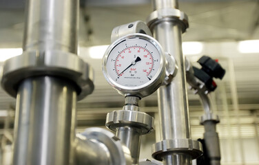 Pressure gauge on industrial piping system for monitoring performance and safety in manufacturing environment