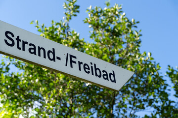Direction sign to beach and outdoor pool in german language