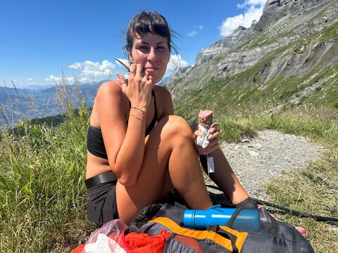 Young woman having a snack while hiking in the Alps, in France