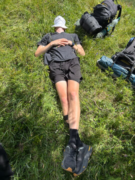 exhausted hiker resting in the grass with hat anon his face
