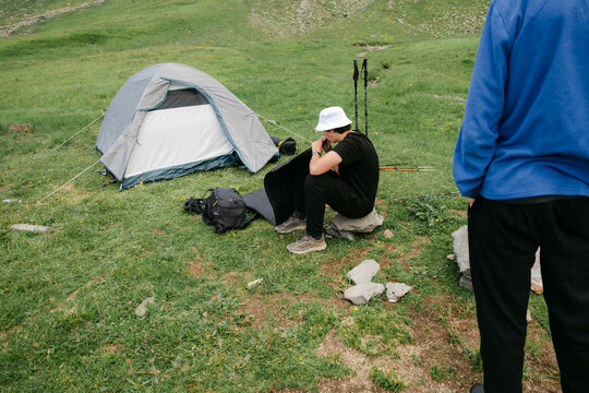 young man blowing up his air mattress to sleep in a tent 