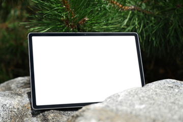 Tablet with blank white screen on rocks in nature background. Blank screen tablet for app design or presentation template.