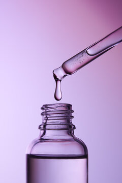 Close-up of a Pipette Releasing Liquid Into a Glass Dropper Bottle.
