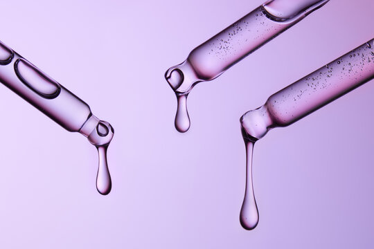 Three glass pipettes with liquid on gradient blue and purple backdrop.