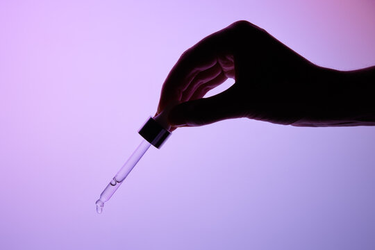 Hand Holding a glass pipette with moisturizer on a Gradient Background