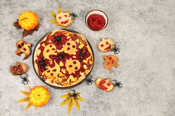 Scary pizza with tomatoes, sausages, ghosts and pumpkins made of cheese and olives on an old concrete background, cafe and menu advertising, restaurant business card, Halloween food concept