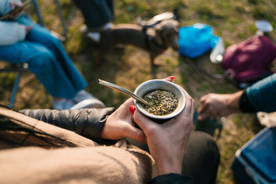 Woman holding calabash with yerba mate during camping trip