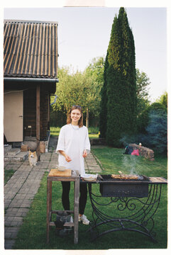 Woman grilling outdoors in backyard garden during sunny afternoon