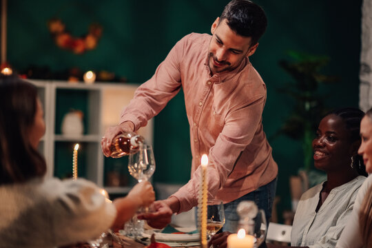 Man pouring wine for friends at thanksgiving dinner table