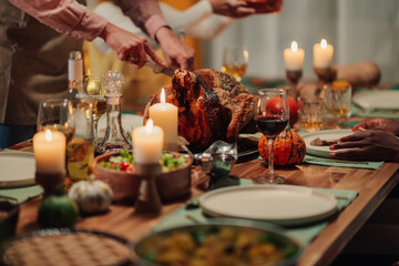 Family celebrating thanksgiving, carving roasted turkey on festive table