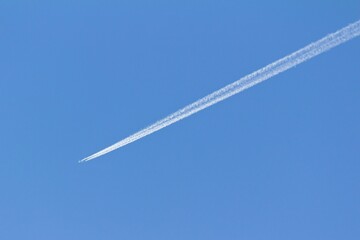 An airplane and its white trail in the blue sky