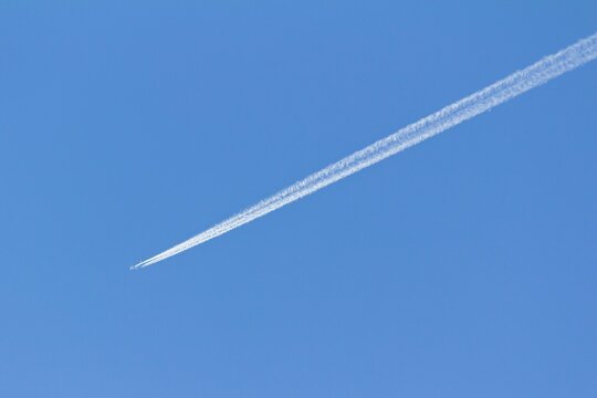 An airplane and its white trail in the blue sky