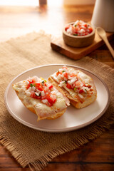 Molletes. Mexican recipe based on bolillo bread split lengthwise, spread with refried beans and gratin cheese, adding pico de gallo sauce and some protein such as ham, bacon or chorizo.