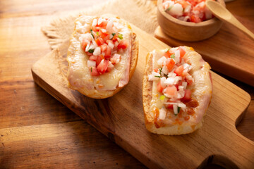 Molletes. Mexican recipe based on bolillo bread split lengthwise, spread with refried beans and gratin cheese, adding pico de gallo sauce and some protein such as ham, bacon or chorizo.