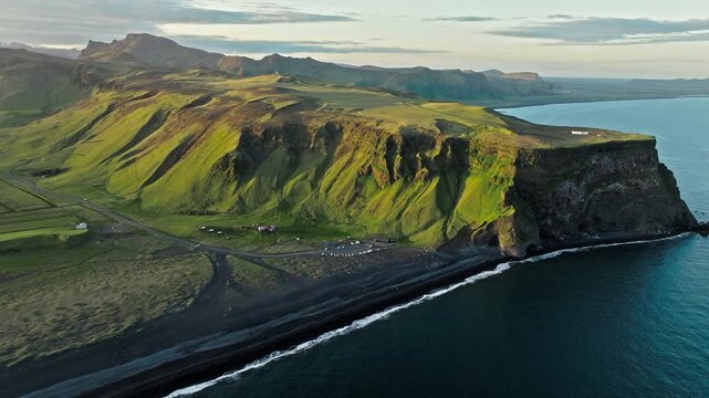 Aerial footage of Reynisfjara Iceland coastline at golden light. Cinematic 4K drone video captures volcanic cliffs, black sand beach, and Atlantic waves in evening tones.
