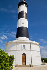 Obraz premium Wide angle view from the entrance of the Phare de Chassiron, showcasing the lighthouse building and its tower.