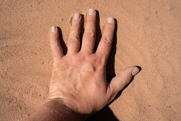 Human hand on sand surface