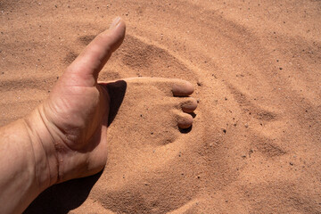 Human hand on sand surface in desert area 