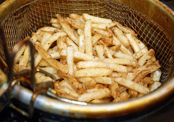 Crispy golden french fries in a deep fryer basket ready to eat 