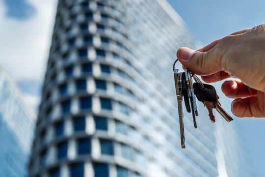 Keys in Hand Against Modern Office Skyscrapers – Real Estate and Investment Concept.  Perfect for business  real estate finance and architecture-related visuals.