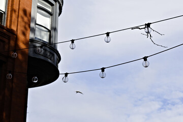 Obraz premium A minimalist urban scene featuring string lights suspended across a soft cloudy sky. 
