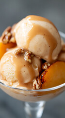 Ice cream with peach and nut toppings, drizzled with caramel in a dessert glass.  Close-up shot of a delightful dessert.  Indulge in delicious flavors.