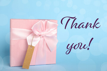 Thank you card design with gift box on light blue background. Bokeh effect