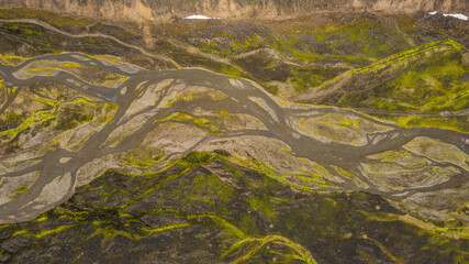 Volcanic Iceland terrain with braided river channels spreading through barren rocky valley seen from drone perspective during summer